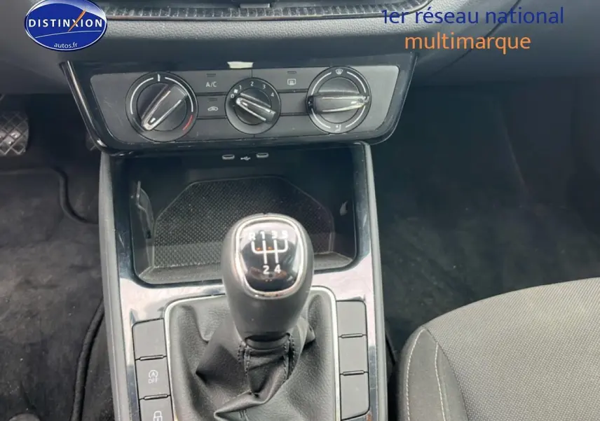 Gros plan sur le levier de vitesses manuel noir et la console centrale d’une Skoda Fabia noire, intérieur tissu gris.
