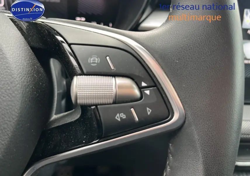 Gros plan sur les commandes multifonctions en aluminium et cuir du volant côté gauche d'une Skoda Fabia noire 2025.