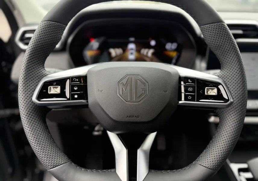 Vue rapprochée du volant perforé noir du MG ZS 1.5L HYBRID+ avec commandes intégrées et logo MG central.