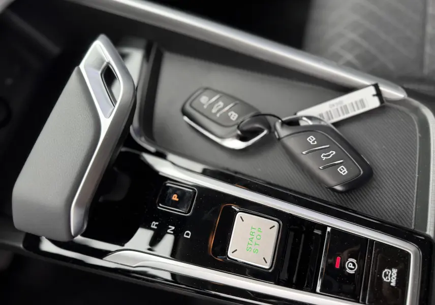 Gros plan sur la console centrale du MG ZS 1.5L Hybrid+ 2026 en Pebble Black, avec levier de vitesses et clés posées.