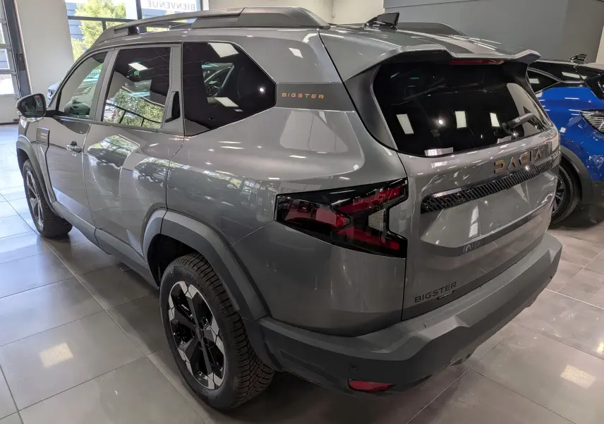 Vue 3/4 arrière droite du Dacia Bigster Hybrid-G 150 gris schiste avec logo et feux arrière LED distinctifs.