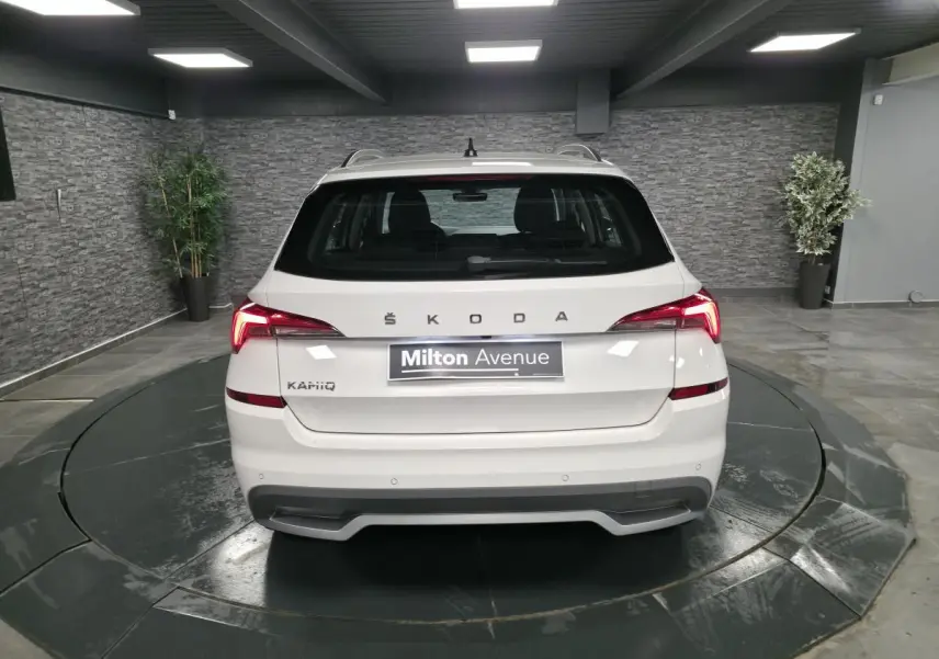 Vue arrière d'un Skoda Kamiq blanc avec feux LED et diffuseur gris platine dans un showroom.