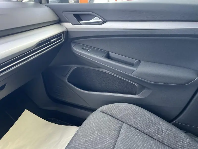 Vue intérieure côté passager avant de la Volkswagen Golf 1.5 eTSI en tissu gris et garnitures noires.
