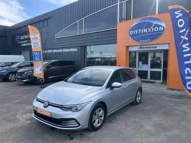 Volkswagen Golf 1.5 eTSI 150ch en Reflet d'Argent métallisé vue 3/4 avant sur parking devant concession Distinxion.