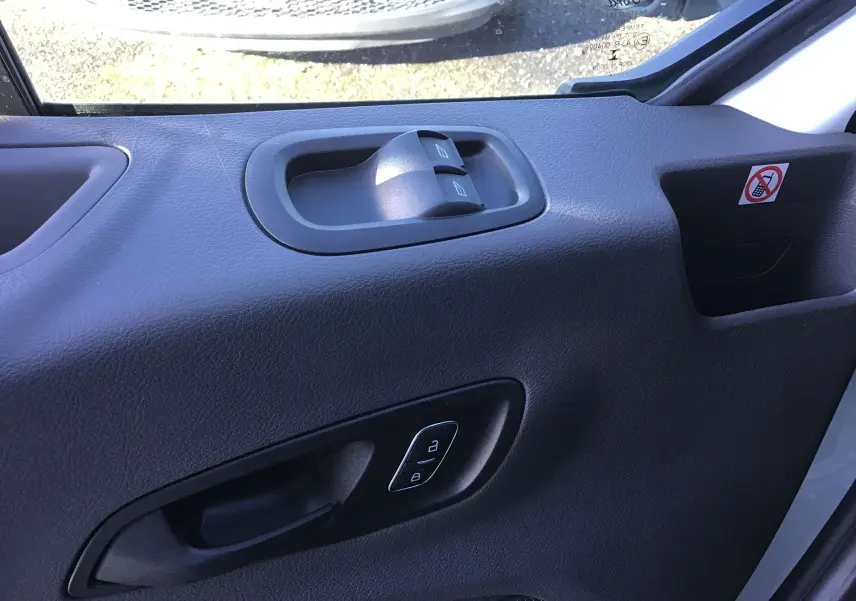 Détail de la porte côté conducteur du Ford Transit blanc, montrant les commandes des vitres et des serrures.