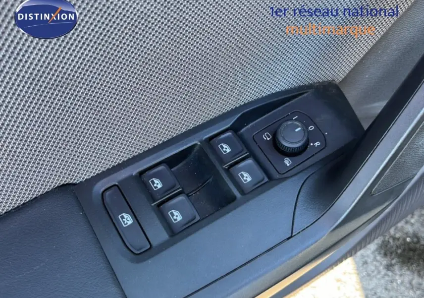 Vue rapprochée sur les commandes de lève-vitres et réglage des rétroviseurs côté conducteur d'une SEAT Leon gris magnétique.