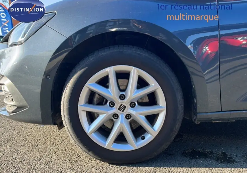 Gros plan sur la roue avant gauche d'une SEAT LEON gris magnétique métal, mettant en valeur la jante alliage distinctive.