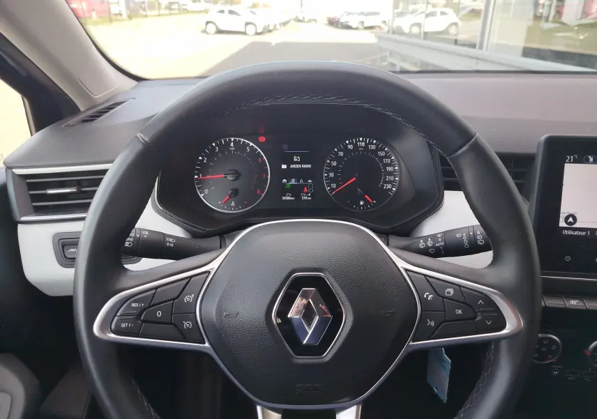 Vue centrée sur le volant noir de la Renault Clio 2022 avec tableau de bord et commandes au volant visibles.
