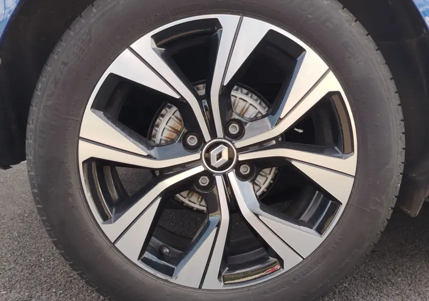 Gros plan sur la jante alliage noire et argentée avec logo Renault, roue avant d'une Clio Bleu Iron 2022.