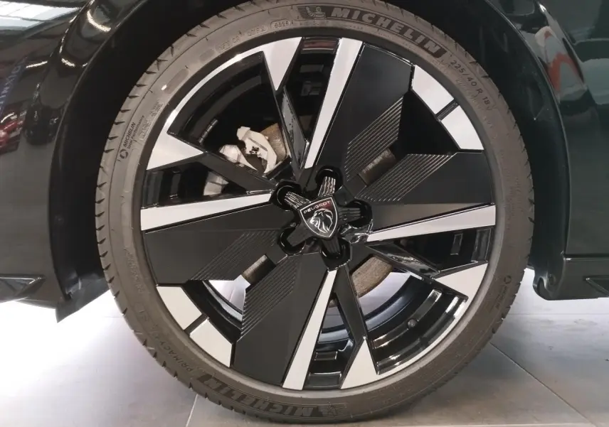 Gros plan sur la jante alliage 18" bi-tons noir et argent avec logo Peugeot sur une 308 noir métal.
