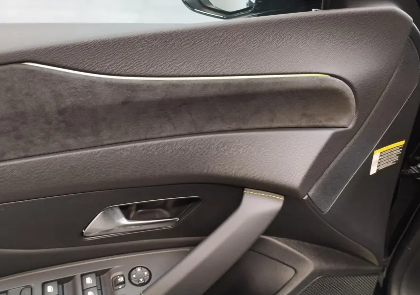 Détail de la porte avant gauche noire avec garniture en similicuir et surpiqûres vert Adamite sur Peugeot 308 Hybrid.