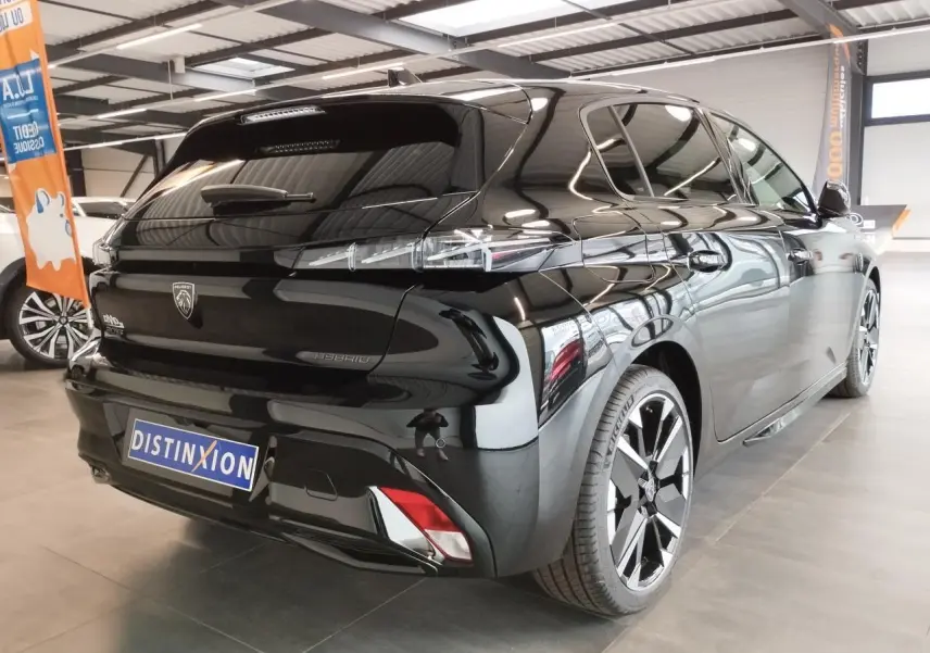Vue 3/4 arrière droite d'une Peugeot 308 Hybrid noire métallisée avec jantes alliage bi-tons et feux arrière LED distinctifs.
