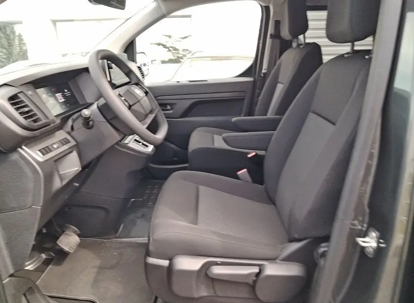 Vue intérieure côté conducteur du Citroën Jumpy Gris Titane 2025, sièges avant avec accoudoirs et volant multifonction.