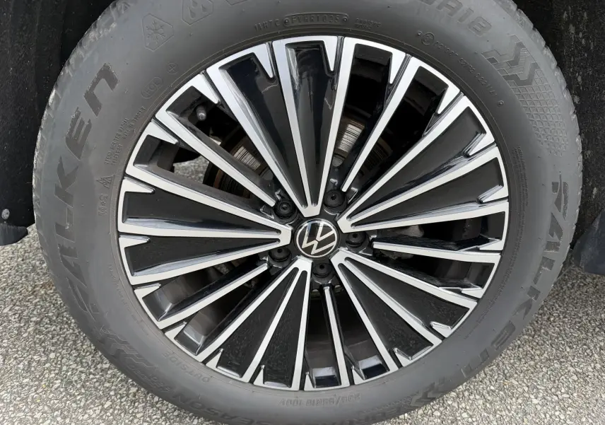 Gros plan sur la jante alliage bicolore noire et argent du Volkswagen Tiguan blanc, mettant en valeur le logo VW central.