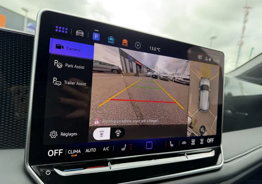 Écran tactile intérieur du Volkswagen Tiguan blanc montrant la caméra de recul et l'assistance au stationnement.