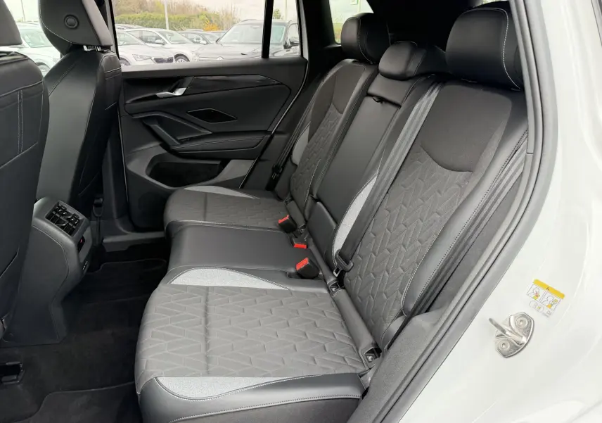 Vue intérieure côté droit des sièges arrière gris et noirs du Volkswagen Tiguan blanc, avec détails de couture apparents.