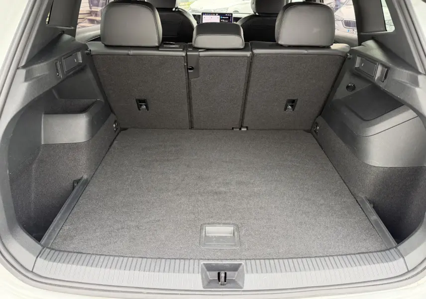 Coffre ouvert vu de l'arrière d'un Volkswagen Tiguan blanc, montrant un espace de chargement propre et spacieux.