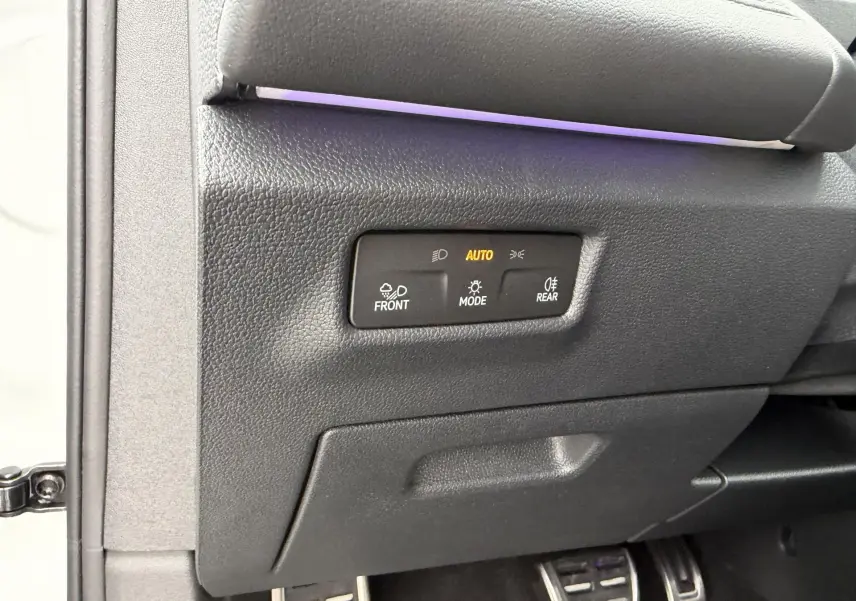 Détail intérieur côté gauche du tableau de bord du Volkswagen Tiguan blanc avec commandes d’éclairage automatiques.
