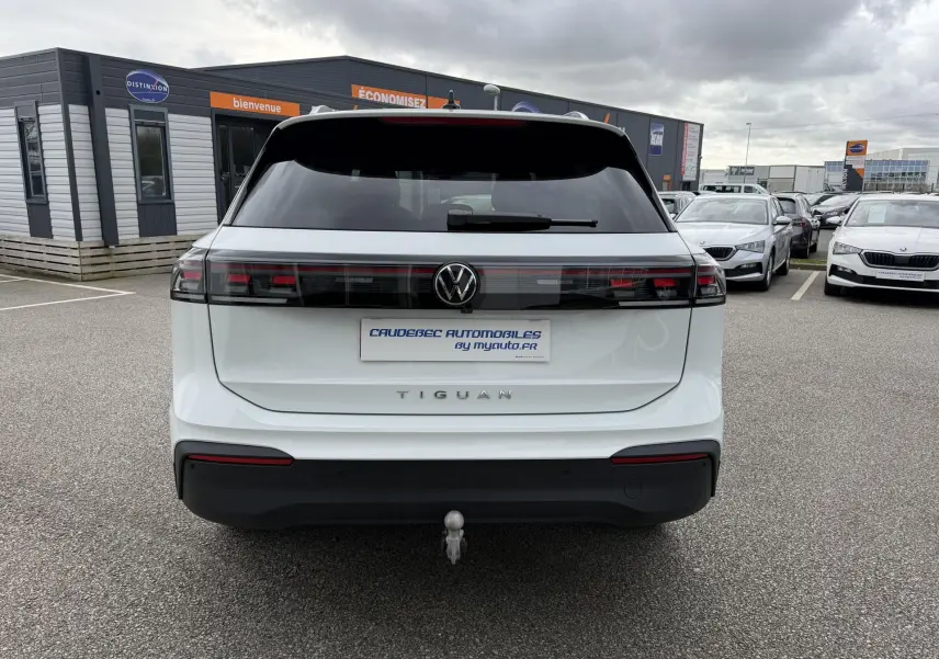 Vue arrière d'un Volkswagen Tiguan blanc 2025 avec attelage rabattable et feux arrière LED noirs.