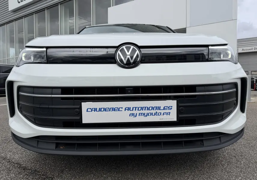 Vue frontale rapprochée du Volkswagen Tiguan blanc avec calandre noire et logo VW central brillant.