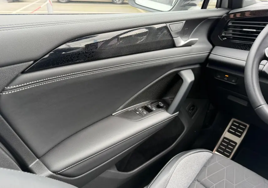 Vue intérieure côté conducteur du Volkswagen Tiguan 2025, avec garniture noire, surpiqûres blanches et commandes électriques.