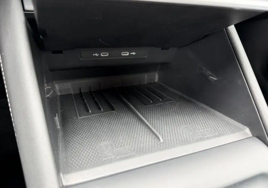 Gros plan sur le compartiment de recharge sans fil noir avec ports USB-C du Volkswagen Tiguan 2025, intérieur sobre.