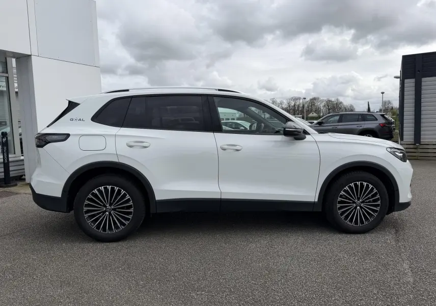Profil droit du Volkswagen Tiguan blanc 2025 avec vitres arrière teintées et jantes alliage noires.