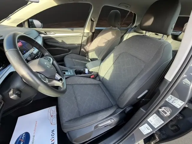 Vue intérieure côté conducteur de la Volkswagen Golf gris clair 2023, montrant les sièges et le volant multifonctions en cuir.