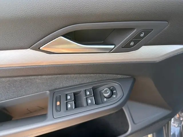 Vue rapprochée de la porte côté conducteur de la Volkswagen Golf gris clair, montrant les commandes de vitres et de verrouillage.