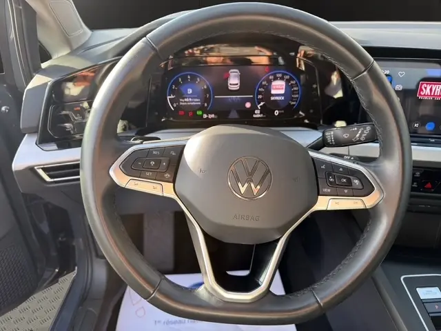 Vue intérieure centrée sur le volant cuir noir de la Volkswagen Golf 2023 avec tableau de bord digital et commandes multifonctions.