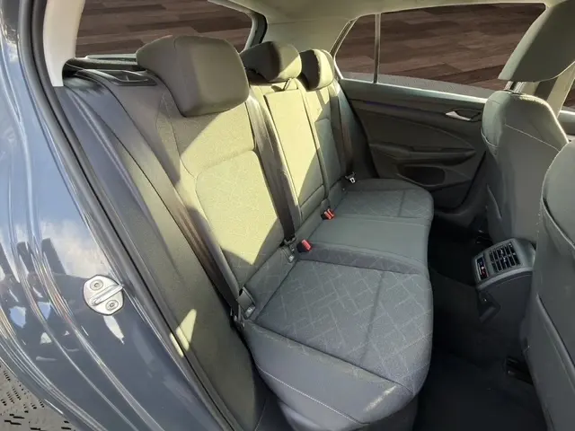 Vue intérieure côté gauche montrant la banquette arrière gris clair de la Volkswagen Golf 2023 avec appuie-têtes et ceintures de sécurité.