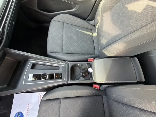 Vue plongeante sur les sièges avant gris foncé et la console centrale avec commandes et porte-gobelets d'une Volkswagen Golf 2023.