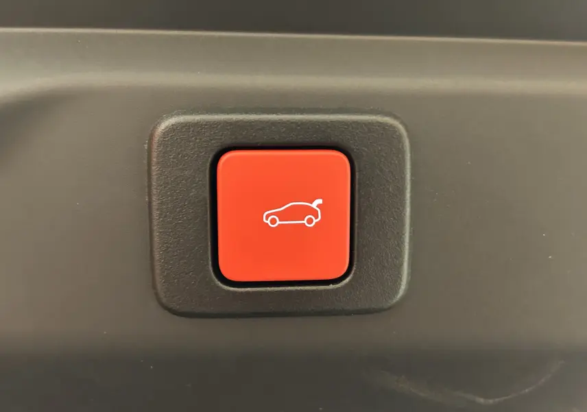 Bouton rouge intérieur avec pictogramme blanc d'ouverture du hayon, détail du Peugeot 3008 Hybrid 2026.