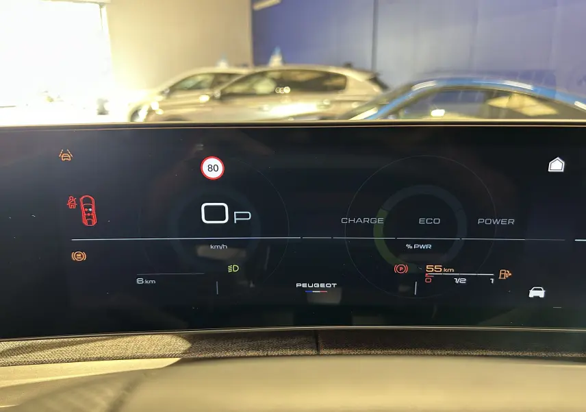 Tableau de bord numérique du Peugeot 3008 Hybrid blanc, affichant la vitesse et l'autonomie en mode stationnement.