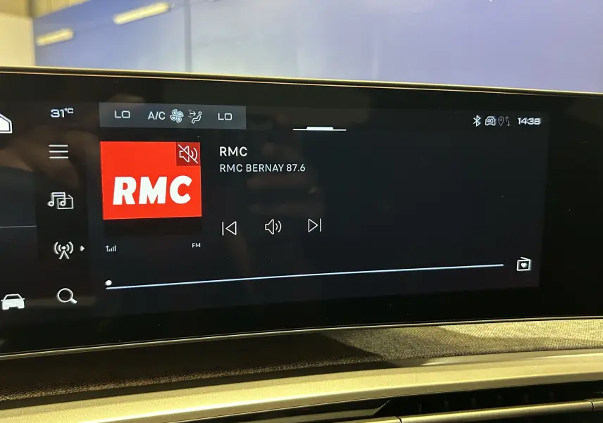 Écran tactile intérieur du Peugeot 3008 Hybrid 2026 affichant la radio RMC avec interface moderne et commandes digitales.