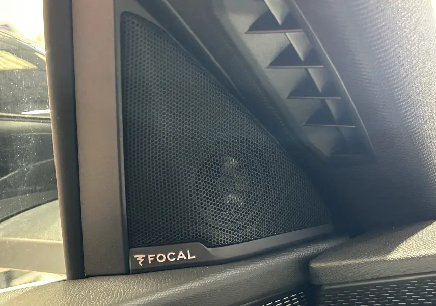 Gros plan sur l’enceinte Focal noire intégrée côté gauche dans l’habitacle du Peugeot 3008 blanc Okenite.