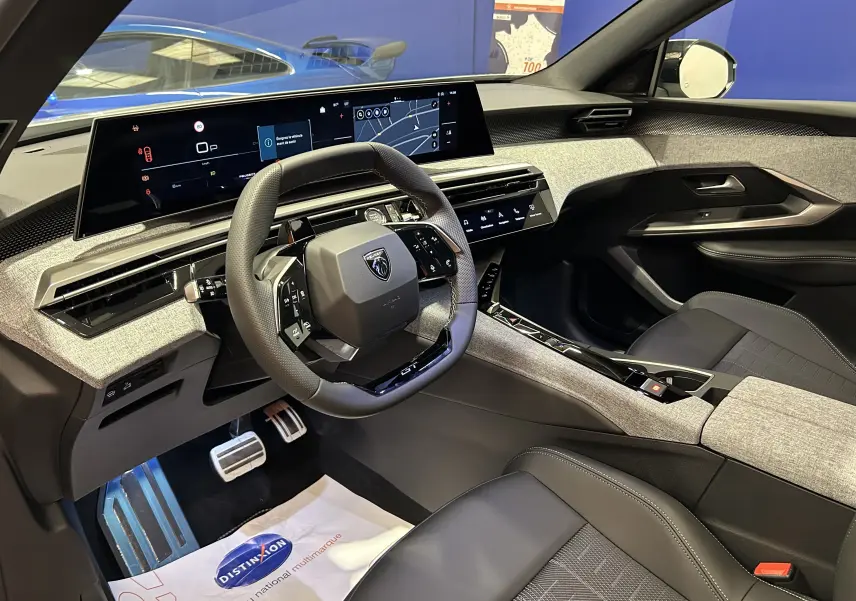 Vue intérieure côté conducteur du Peugeot 3008 Hybrid 2026, tableau de bord numérique et finition tissu gris clair avec cuir noir.