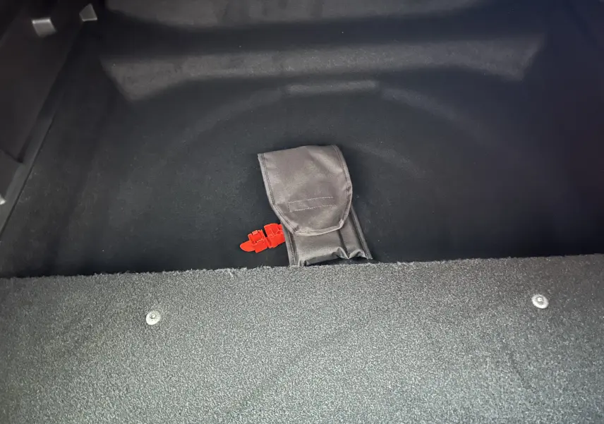 Coffre ouvert du Peugeot 3008 blanc, montrant un rangement noir avec une sangle rouge visible au centre.