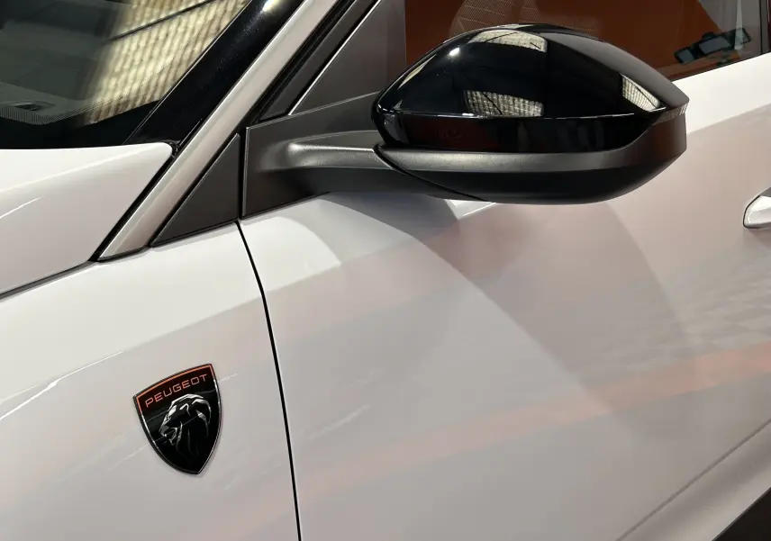 Détail du côté gauche blanc Okenite du Peugeot 3008 Hybrid avec rétroviseur noir brillant et logo Peugeot noir et cuivre.
