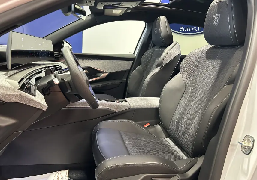 Vue intérieure côté gauche du Peugeot 3008 Hybrid 2026 avec sièges en cuir noir et tissu gris, volant compact et tableau de bord numérique.
