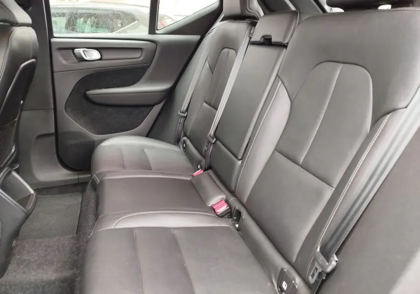 Vue intérieure côté droit des sièges arrière en cuir noir du Volvo XC40 beige, mettant en valeur les ceintures de sécurité et les finitions.