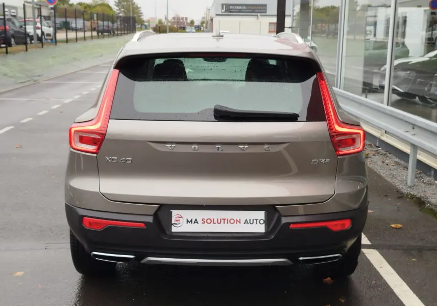 Vue arrière d'un Volvo XC40 beige 2020 avec feux LED caractéristiques et double sortie d'échappement intégrée.