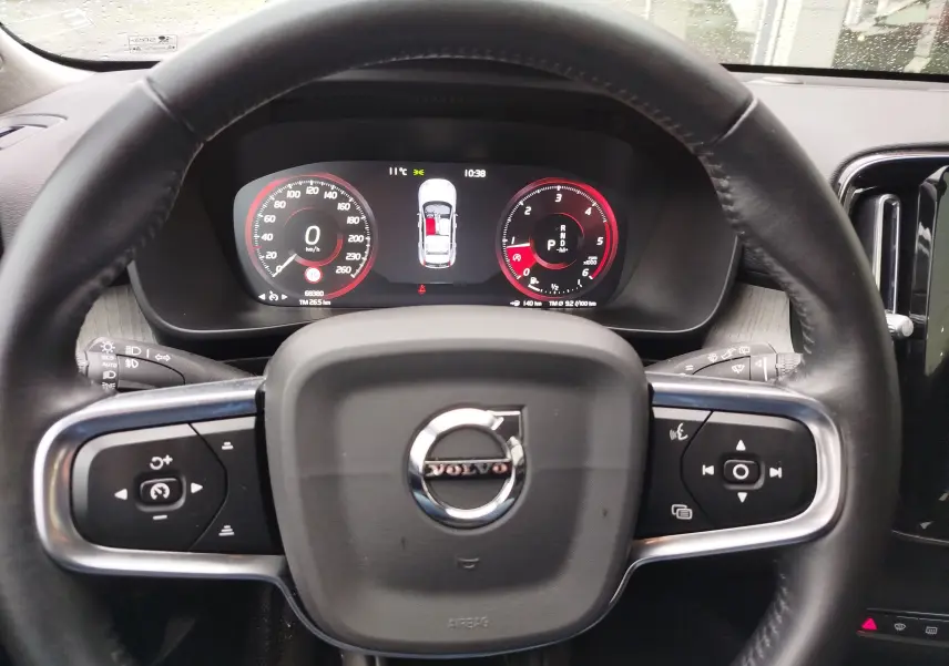 Vue intérieure centrée sur le volant noir et le tableau de bord numérique du Volvo XC40 beige de 2020.