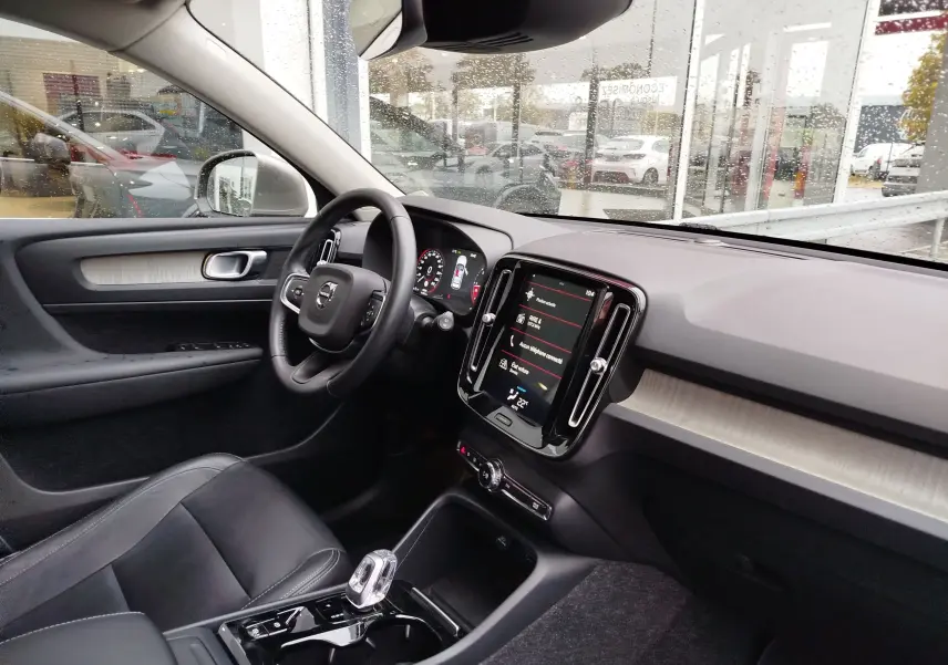 Vue intérieure côté conducteur du Volvo XC40 beige 2020, avec tableau de bord moderne et écran tactile central.