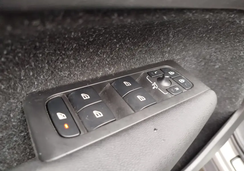 Gros plan sur les commandes des vitres et rétroviseurs côté conducteur du Volvo XC40 beige de 2020.