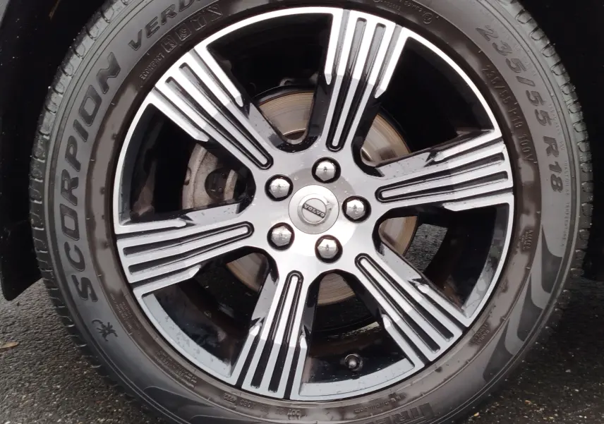 Gros plan sur la jante alliage bicolore noire et argentée d’un Volvo XC40 beige, avec pneu Pirelli Scorpion Verde.