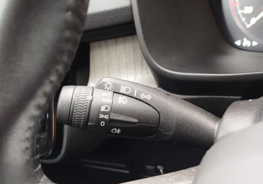 Gros plan sur la manette de commande des phares à gauche du volant dans l’habitacle beige du Volvo XC40 D3 2020.