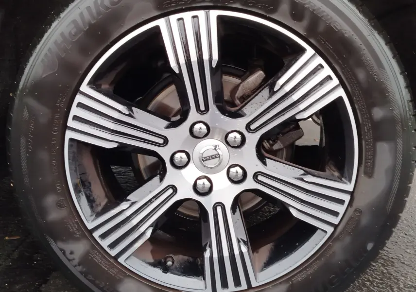 Gros plan sur la jante alliage bicolore noire et argentée du Volvo XC40 beige, mettant en valeur le logo central Volvo.
