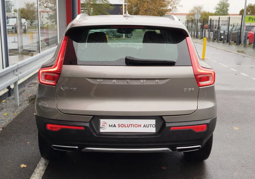 Vue arrière d'un Volvo XC40 beige 2020 avec feux LED caractéristiques et double sortie d'échappement chromée.