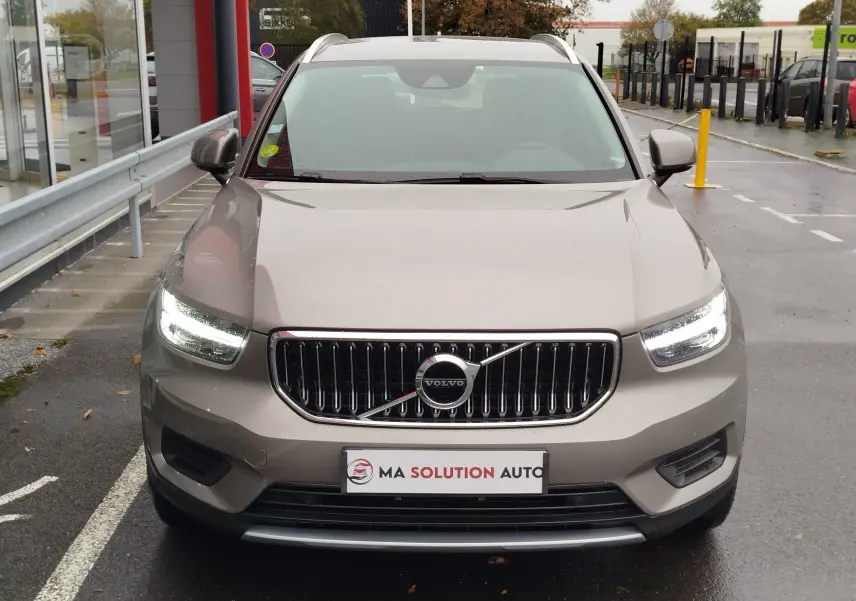 Vue frontale d'un Volvo XC40 beige 2020 avec phares allumés, calandre chromée et plaque "Ma Solution Auto".
